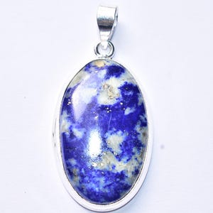以下が含まれることがあります： 深い青色のラピスラズリの石を使った楕円形のペンダント。白い斑点と金色のインクルージョンがあり、銀色の金属フレームにセットされています。ペンダントにはネックレス用の銀色のベイルが付いています。