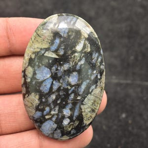 May include: A white ceramic mug with a black handle and the text "But First, Coffee" in a bold, black font. The mug is set against a blurred background, suggesting a cosy setting.