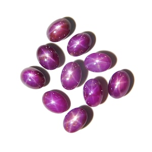 Könnte beinhalten: Zehn ovale, violette Stern-Saphire mit einem sternförmigen Muster in der Mitte jedes Steins.