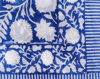 May include: A white cotton fabric with a blue floral pattern. The fabric has a border of blue stripes.