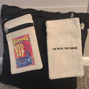 May include: Two small, beige canvas pouches with black zippers. One pouch has a colorful graphic with the text "LOLLAPALOOZA 1994 VIP". The other pouch has the text "I'M WITH THE BAND" in black.