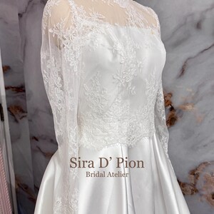 Beautiful wedding dress topper, Alecon Lace bridal topper, handcrafted in Florida. Highe neck, long sleeves and cover buttons. A white lace wedding dress bodice with a high neck and long sleeves. The lace is delicate and features floral patterns.
