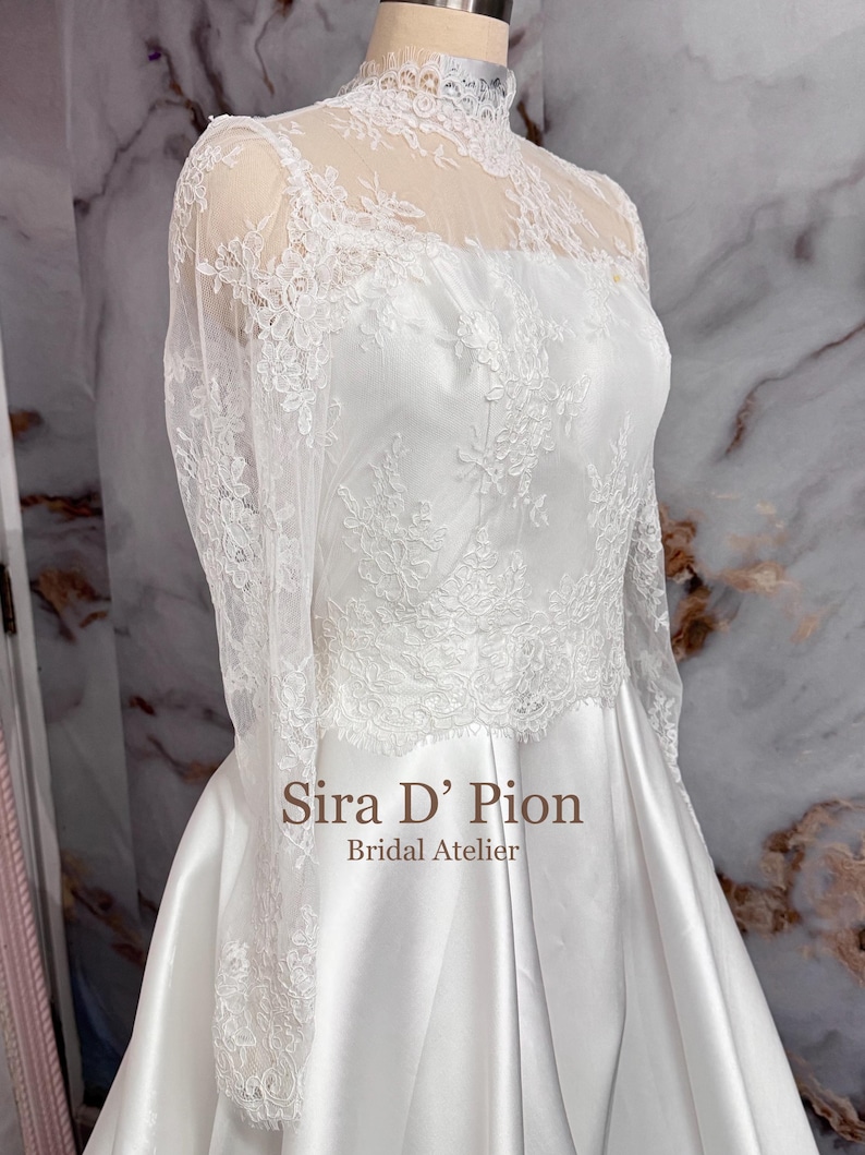 Beautiful wedding dress topper, Alecon Lace bridal topper, handcrafted in Florida. Highe neck, long sleeves and cover buttons. A white lace wedding dress bodice with a high neck and long sleeves. The lace is delicate and features floral patterns.