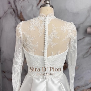 Beautiful wedding dress topper, Alecon Lace bridal topper, handcrafted in Florida. Highe neck, long sleeves and cover buttons. A white lace wedding dress bodice with a high neck and long sleeves. The lace is delicate and features floral patterns.