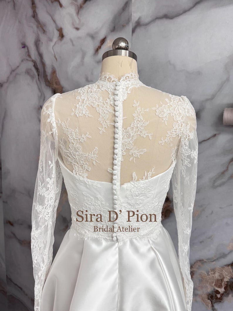 Beautiful wedding dress topper, Alecon Lace bridal topper, handcrafted in Florida. Highe neck, long sleeves and cover buttons. A white lace wedding dress bodice with a high neck and long sleeves. The lace is delicate and features floral patterns.