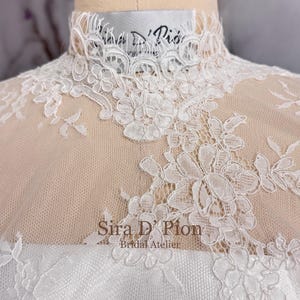 Beautiful wedding dress topper, Alecon Lace bridal topper, handcrafted in Florida. Highe neck, long sleeves and cover buttons. A white lace wedding dress bodice with a high neck and long sleeves. The lace is delicate and features floral patterns.