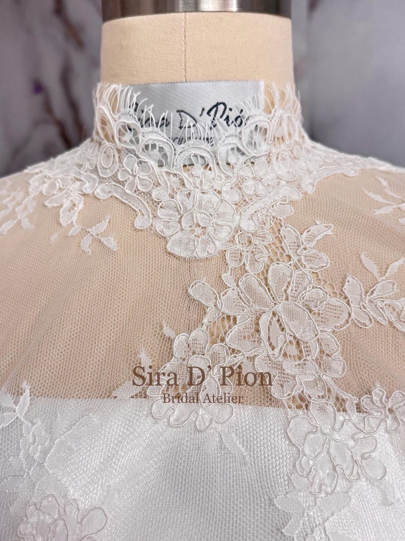 Beautiful wedding dress topper, Alecon Lace bridal topper, handcrafted in Florida. Highe neck, long sleeves and cover buttons. A white lace wedding dress bodice with a high neck and long sleeves. The lace is delicate and features floral patterns.
