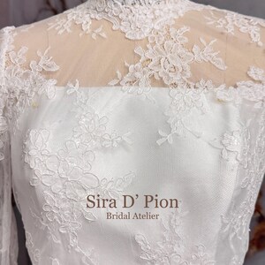 Beautiful wedding dress topper, Alecon Lace bridal topper, handcrafted in Florida. Highe neck, long sleeves and cover buttons. A white lace wedding dress bodice with a high neck and long sleeves. The lace is delicate and features floral patterns.