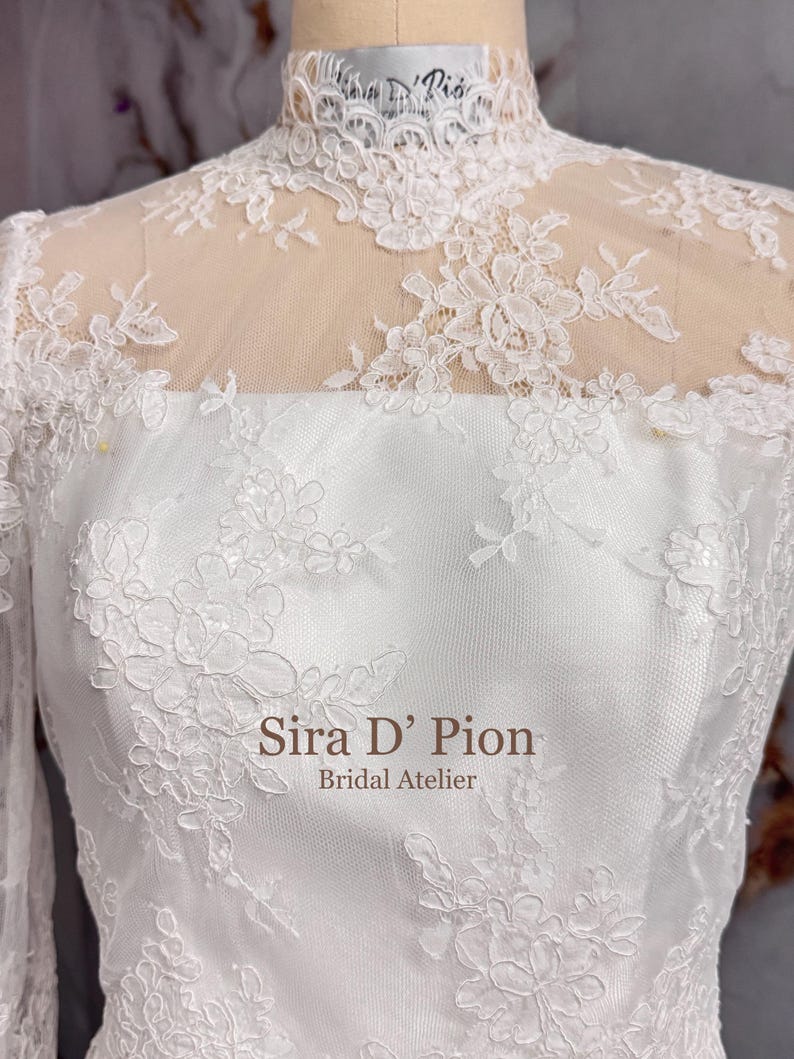 Beautiful wedding dress topper, Alecon Lace bridal topper, handcrafted in Florida. Highe neck, long sleeves and cover buttons. A white lace wedding dress bodice with a high neck and long sleeves. The lace is delicate and features floral patterns.