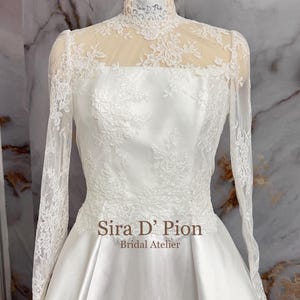 Beautiful wedding dress topper, Alecon Lace bridal topper, handcrafted in Florida. Highe neck, long sleeves and cover buttons. A white lace wedding dress bodice with a high neck and long sleeves. The lace is delicate and features floral patterns.