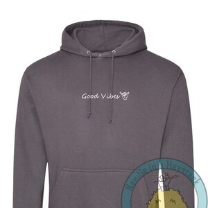 May include: A charcoal gray hoodie with a white graphic that says "Good Vibes" and a hand gesture. The hoodie has a drawstring hood and a kangaroo pocket.