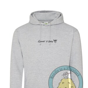 May include: A gray hooded sweatshirt with the text "Good Vibes" and a hand gesture on the front. The sweatshirt has a logo on the sleeve that says "Needle in a Haystack Adventure Clothing".