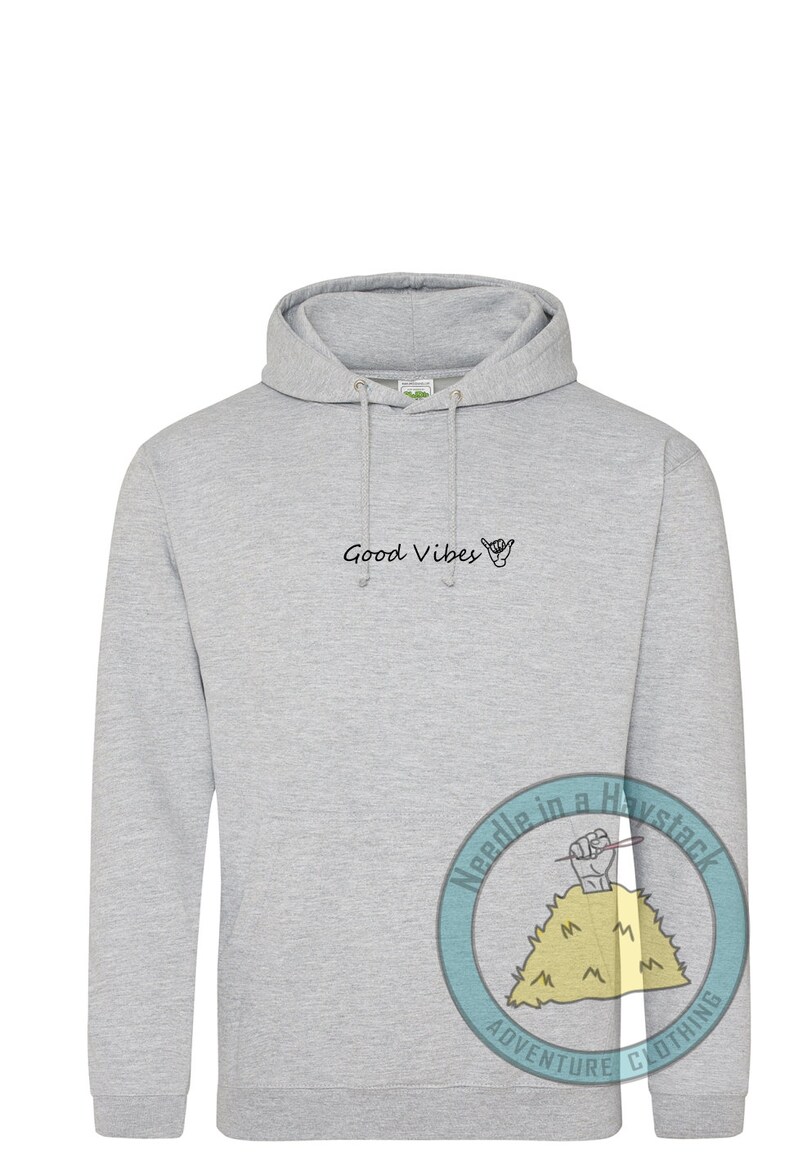 May include: A gray hooded sweatshirt with the text "Good Vibes" and a hand gesture on the front. The sweatshirt has a logo on the sleeve that says "Needle in a Haystack Adventure Clothing".
