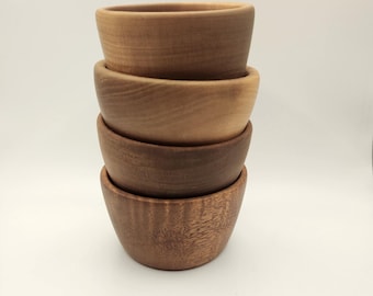 May include: Four wooden bowls stacked on top of each other. The bowls are all different sizes and shades of brown.