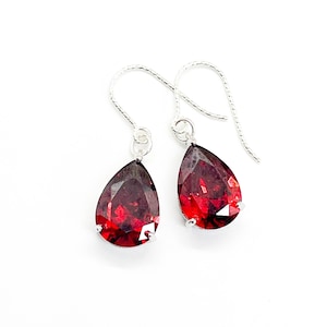 Peut inclure: Une paire de boucles d'oreilles pendantes en argent avec des pierres précieuses rouges en forme de goutte.