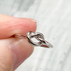 May include: A silver knot ring with a simple design.