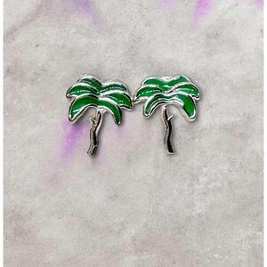 May include: A pair of silver palm tree earrings with green enamel leaves.