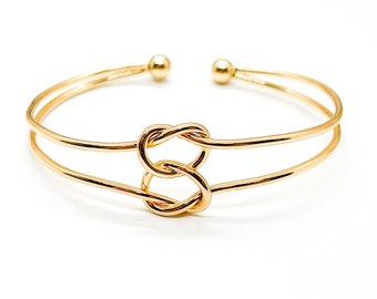 Peut inclure: Un bracelet jonc double en or avec un motif de nœud.