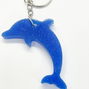 May include: A blue glitter dolphin keychain with a silver key ring.