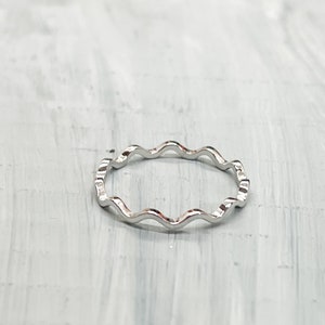 May include: A silver ring with a wavy, textured design.