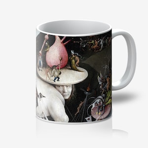 May include: White ceramic coffee mug featuring a detail from a Hieronymus Bosch painting. The artwork depicts fantastical figures and scenes in a dark, surreal style. The mug has a white handle and interior.