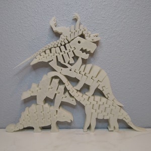 May include: A set of five white plastic dinosaur skeletons stacked on top of each other. The skeletons are articulated and can be posed in different ways.