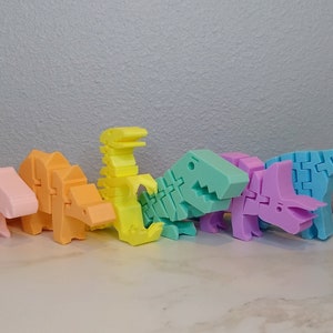 May include: A set of seven pastel-colored dinosaur toys made of plastic. The dinosaurs are arranged in a row from left to right, with the smallest dinosaur on the left and the largest dinosaur on the right. The dinosaurs are all different colors, including pink, orange, yellow, green, purple, and blue.