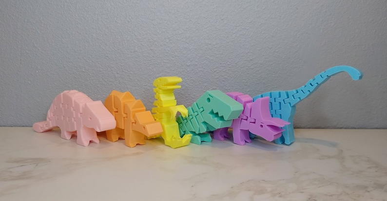 May include: A set of seven pastel-colored dinosaur toys made of plastic. The dinosaurs are arranged in a row from left to right, with the smallest dinosaur on the left and the largest dinosaur on the right. The dinosaurs are all different colors, including pink, orange, yellow, green, purple, and blue.