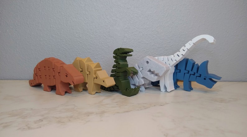 May include: A set of six colorful dinosaur toys made of plastic. The dinosaurs are in various poses, including standing, walking, and running. The dinosaurs are all different colors, including red, brown, green, white, and blue.