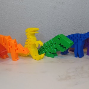 May include: Six colorful dinosaur toys made of plastic, arranged in a row. The dinosaurs are red, orange, yellow, green, blue, and purple.