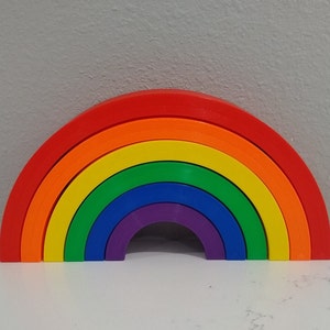 May include: A rainbow-colored stacking toy made of plastic. The toy is shaped like an arch and has seven different colored rings.