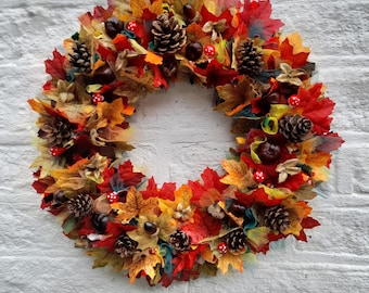 May include: A fall-themed wreath with red, orange, and yellow leaves, pinecones, and berries.
