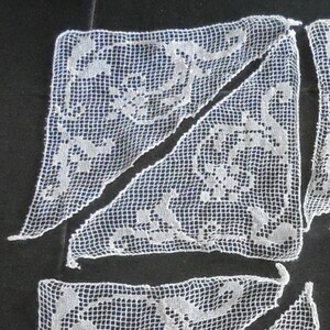 May include: Nine white crocheted lace doilies in a triangular shape with a floral pattern.