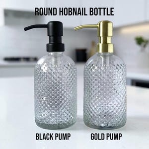 May include: Two round hobnail bottles with clear glass bodies and pump dispensers. One bottle features a matte black pump, while the other has a brushed gold pump. The text ROUND HOBNAIL BOTTLE, BLACK PUMP, and GOLD PUMP is visible in the image.