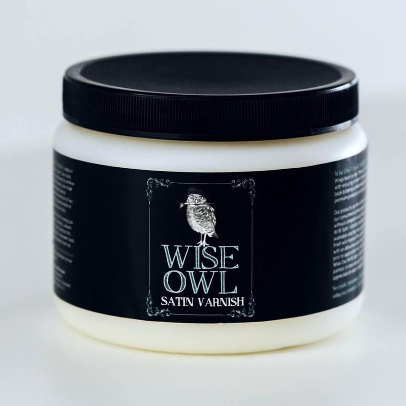 May include: A white plastic jar with a black lid and a black label. The label features a stylised illustration of an owl with the text "WISE OWL SATIN VARNISH".