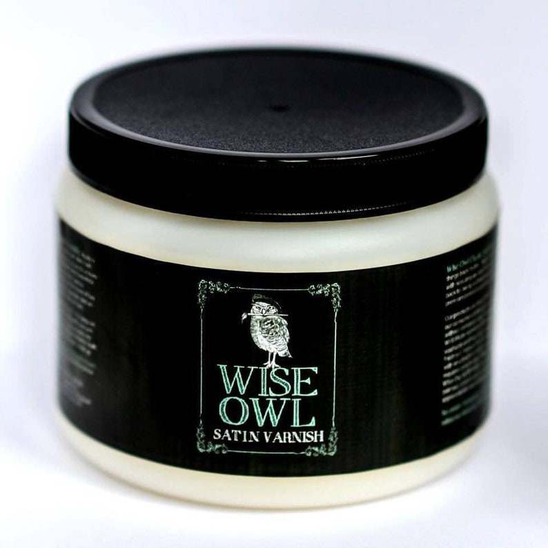 May include: A white plastic jar with a black lid and a black label. The label features a green and white illustration of an owl and the text "WISE OWL SATIN VARNISH".