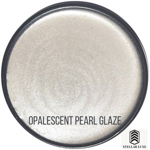 May include: A round container of iridescent white opal glaze with the text "OPALESCENT PEARL GLAZE" and the logo "STELLAR LUXE" in black.