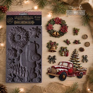 May include: A grey silicone decor mould labelled Country Christmas Delivery featuring various holiday shapes. Beside it are finished castings including a poinsettia wreath, bells, gift boxes, a bow, and a red truck carrying a Christmas tree.