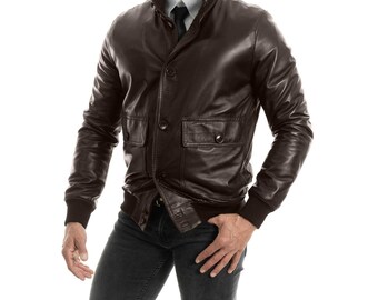 May include: A brown leather bomber jacket with a button closure and a stand-up collar.