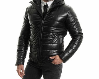 May include: A black leather puffer jacket with a zipper closure and a hood. The jacket has a quilted design and a stand-up collar.
