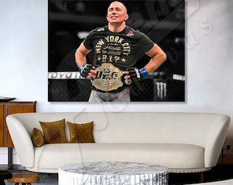May include: A man wearing a black t-shirt with the text "New York City" and "The Place to Hide 2017" in gold lettering. He is holding a UFC championship belt in front of him. The belt is gold with black and white accents. The man is standing in a boxing ring.