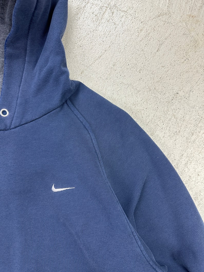 May include: A navy blue hooded sweatshirt with a white Nike swoosh logo on the front.