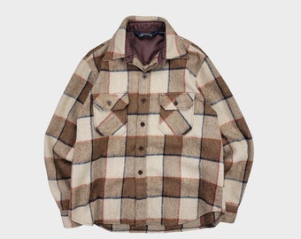 May include: A brown, beige, and blue plaid flannel shirt with a button-up front and two chest pockets.