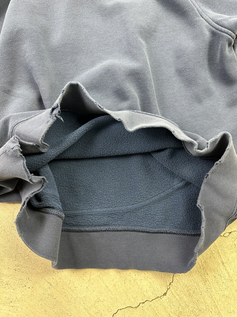May include: A dark gray sweatshirt with a fleece lining. The sweatshirt is turned inside out to show the lining.