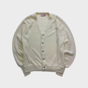 Peut inclure: Un cardigan en laine jaune pâle avec un col en V et une fermeture à boutons.