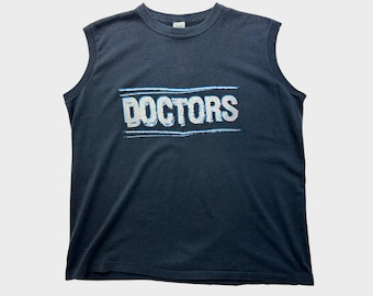 May include: A black sleeveless t-shirt with the word "DOCTORS" printed in white with a blue outline.