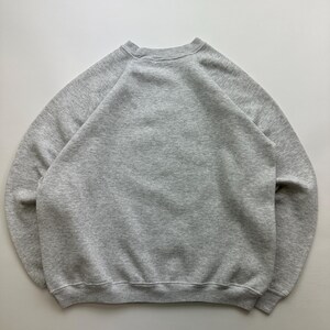 May include: A gray sweatshirt with a crew neck and long sleeves. The sweatshirt is made of a soft, comfortable material.