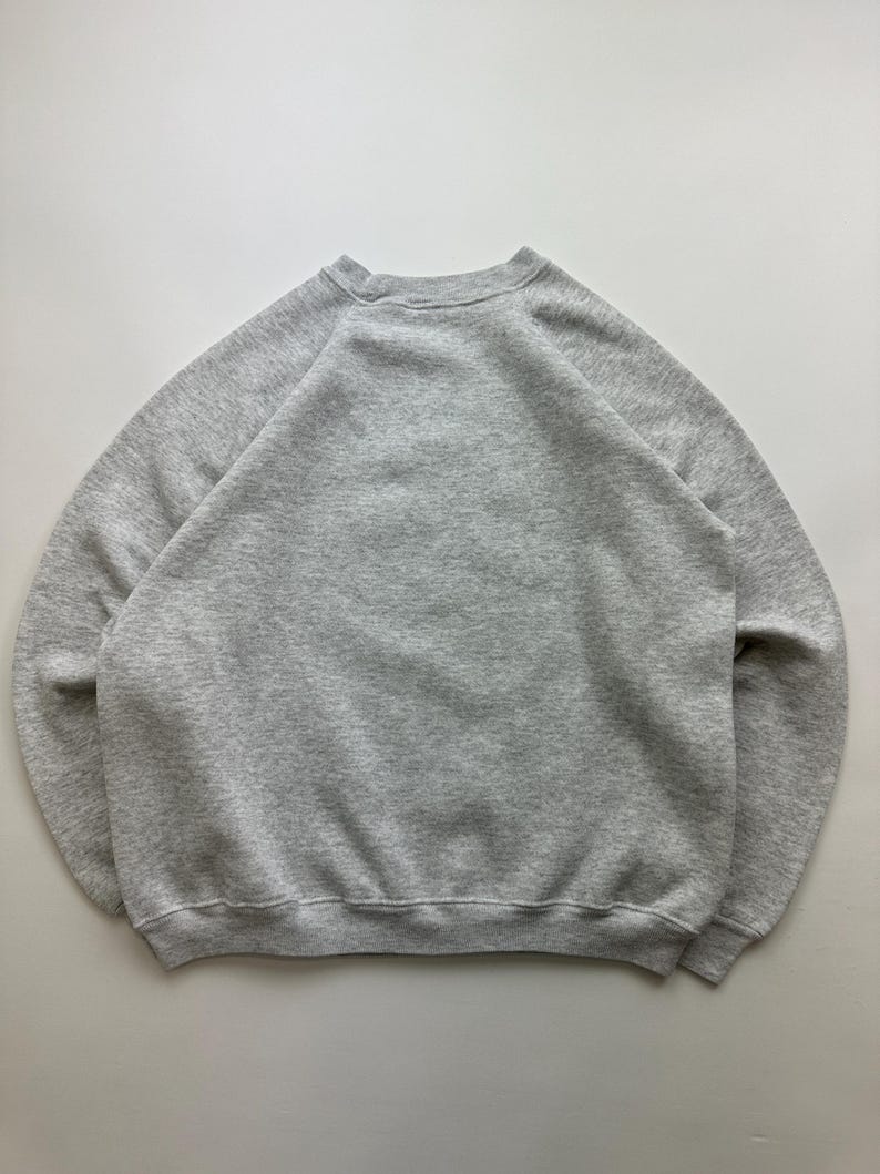 May include: A gray sweatshirt with a crew neck and long sleeves. The sweatshirt is made of a soft, comfortable material.
