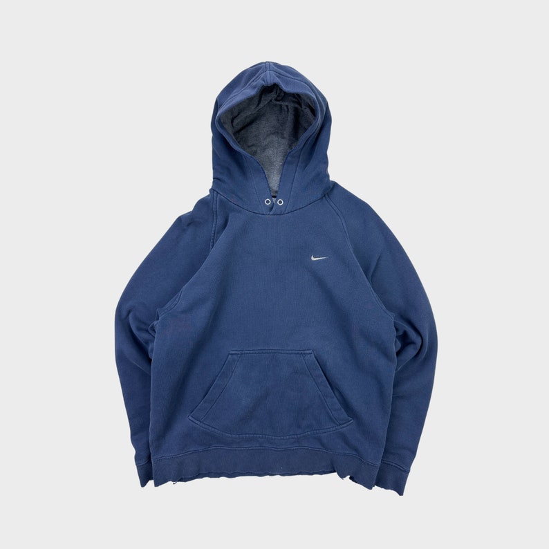 May include: A navy blue hooded sweatshirt with a small white Nike swoosh logo on the left chest. The sweatshirt has a kangaroo pocket and a drawstring hood.