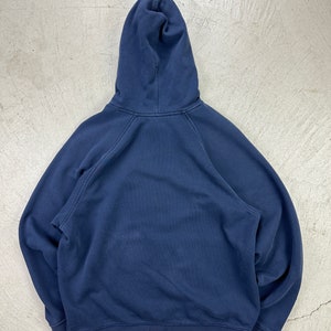 May include: A dark blue hooded sweatshirt with a drawstring hood. The sweatshirt has long sleeves and a kangaroo pocket.